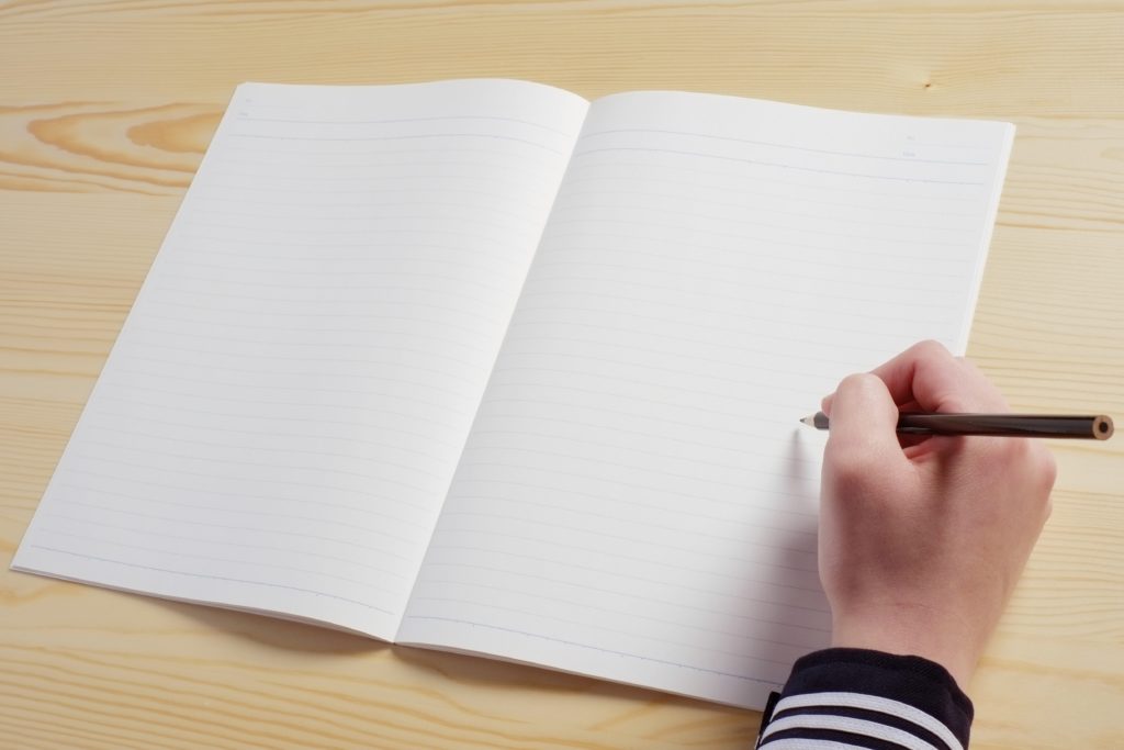 uma mão escrevendo em um caderno